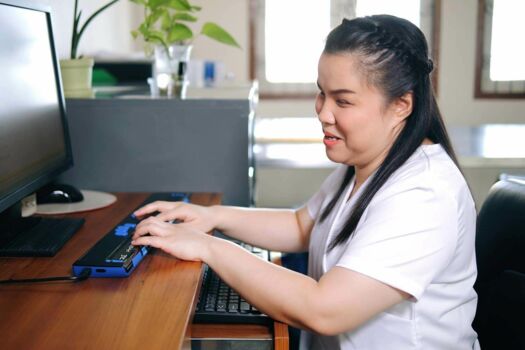 eine blinde Frau, die einen Computer eine aktualisierbare Braillezeile benutzt